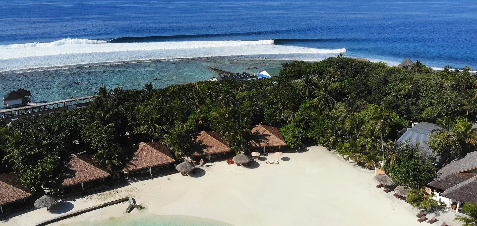 Surfer performing maneuver on a large curling wave in Maldives – Atoll Travel